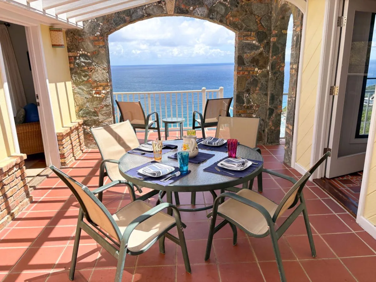 Una zona de comedor en el patio con la mesa puesta y vistas al mar.