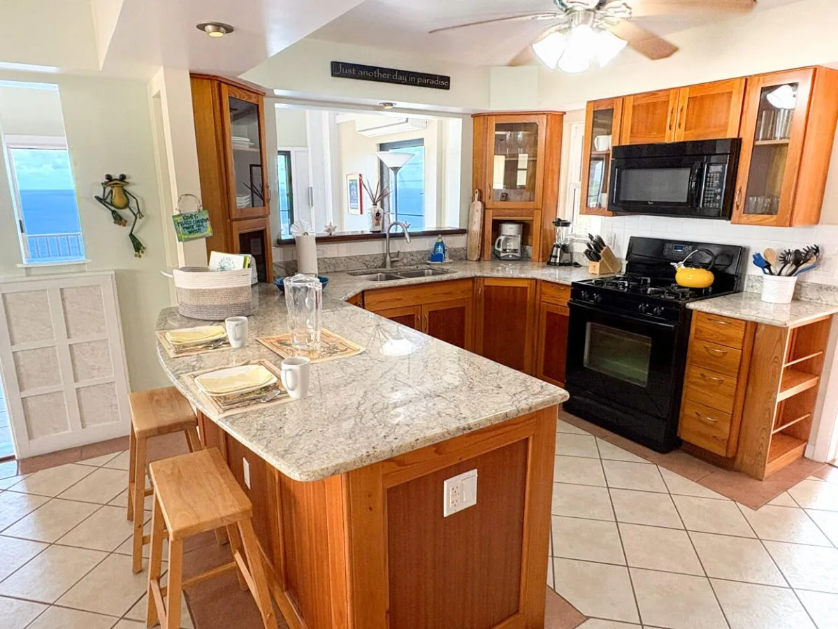 Una cocina luminosa con gabinetes de madera, una isla central y una estufa negra.