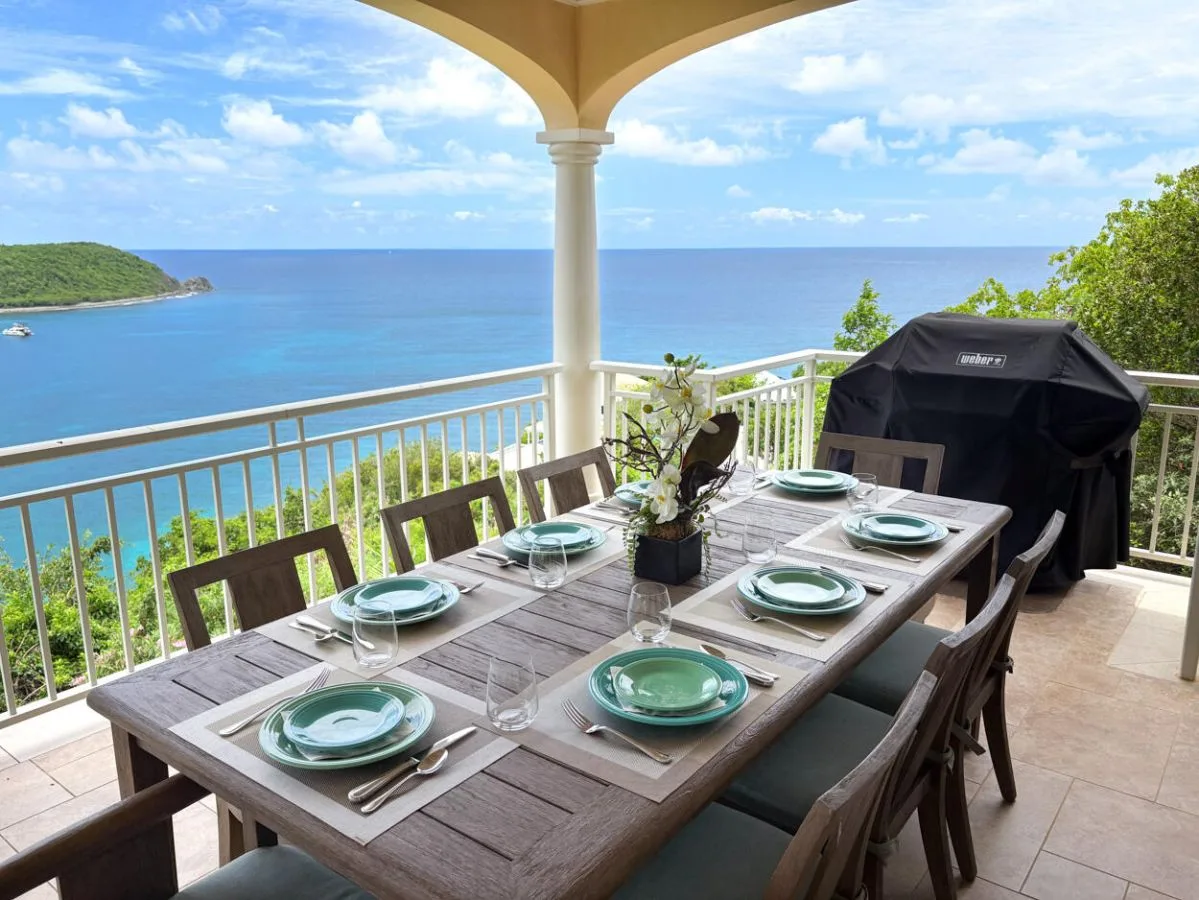 Comedor al aire libre con la mesa puesta y vistas al mar.