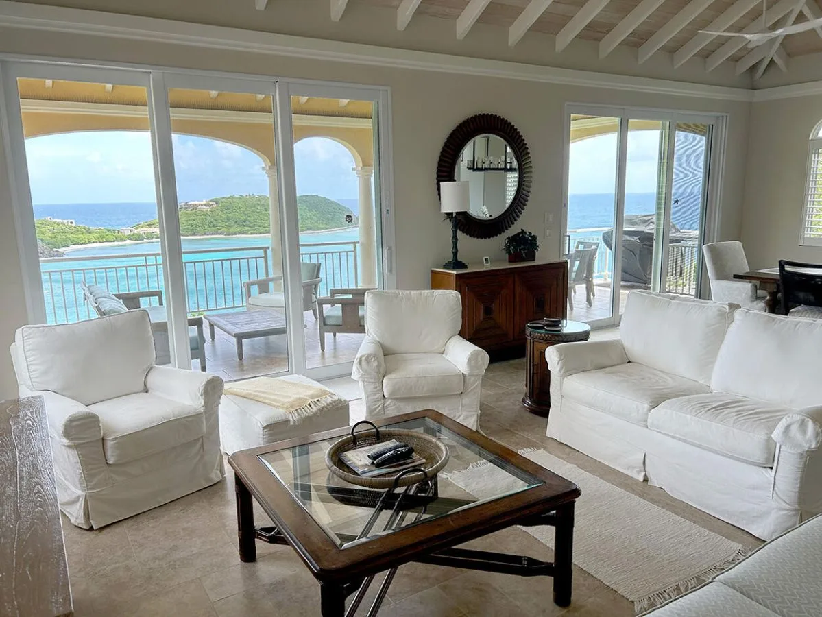 Una sala luminosa con asientos blancos y grandes ventanales con vistas al agua.