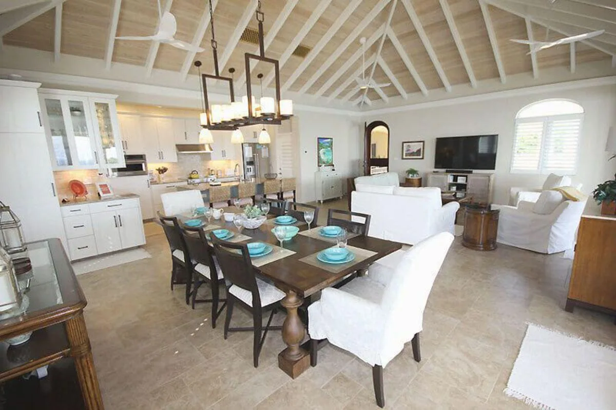 Un comedor y sala de estar de concepto abierto, con una mesa bajo un techo abovedado.