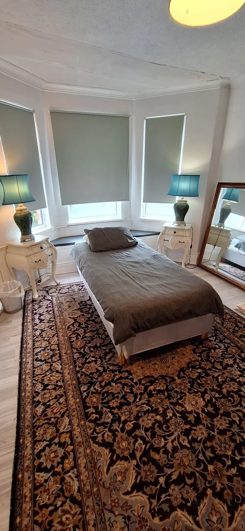A bedroom with a bed between two bedside tables and a patterned rug.