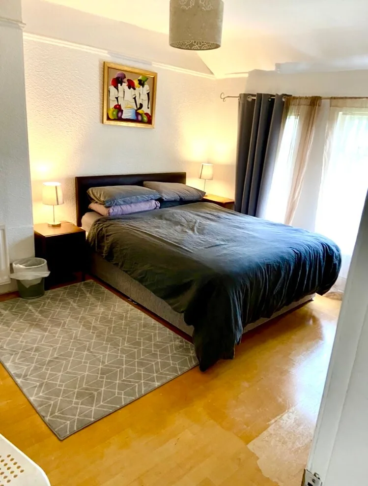 A bedroom with a large bed, bedside tables, and curtains beside a window.