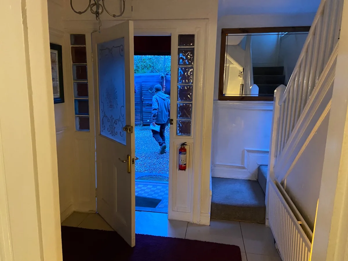 An entry hall with an open front door and a staircase along the wall.