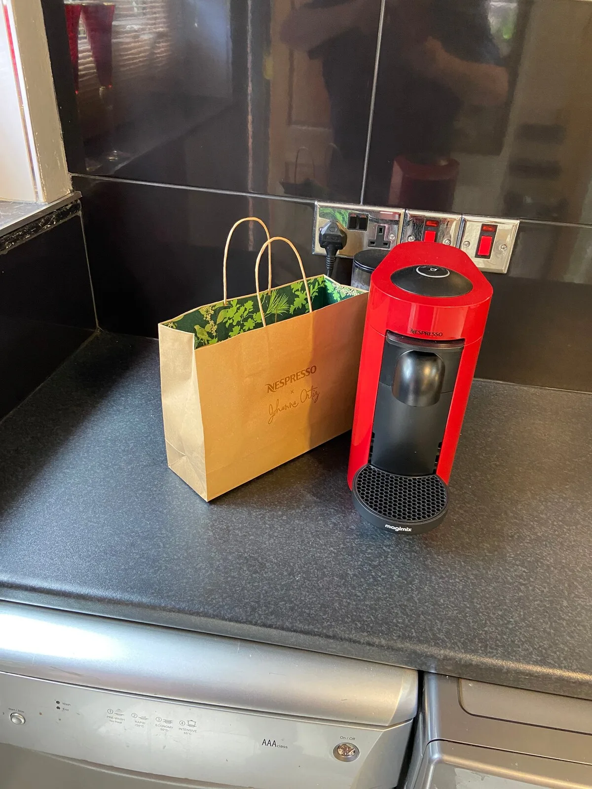 A kitchen counter holds a paper bag beside a red coffee machine.