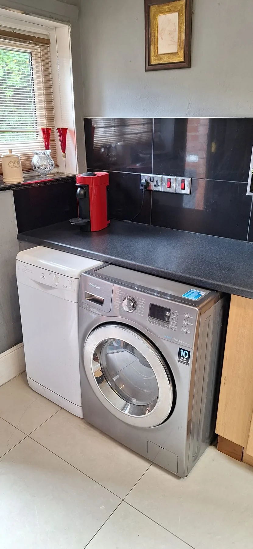 A laundry area with a washing machine and counter beneath a window.