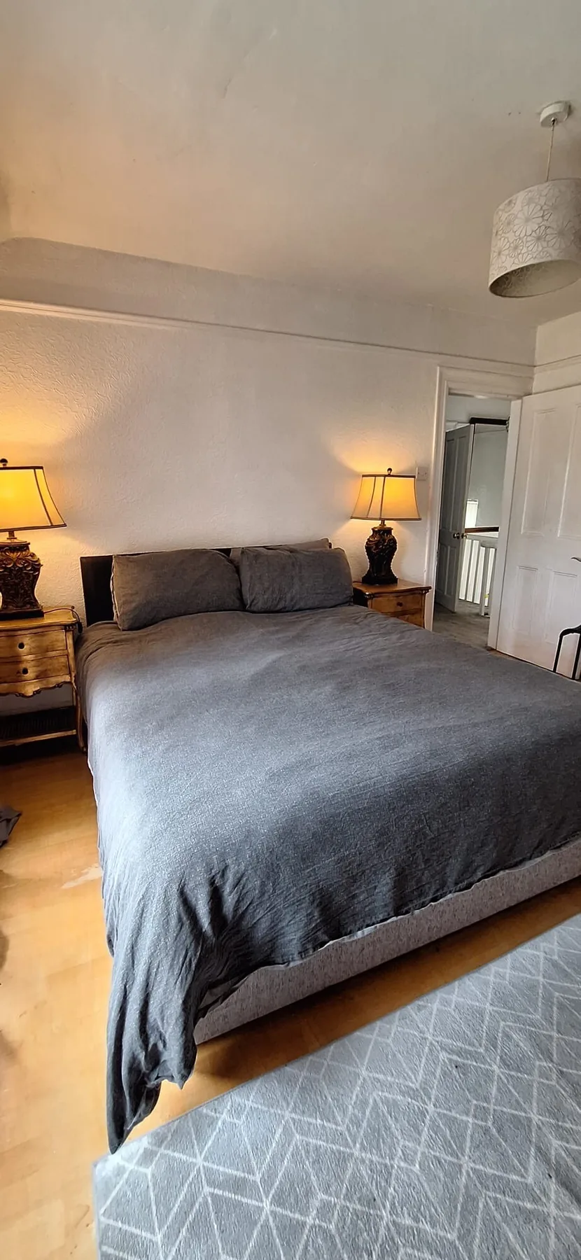A bedroom with a large bed, bedside tables, and a patterned rug.
