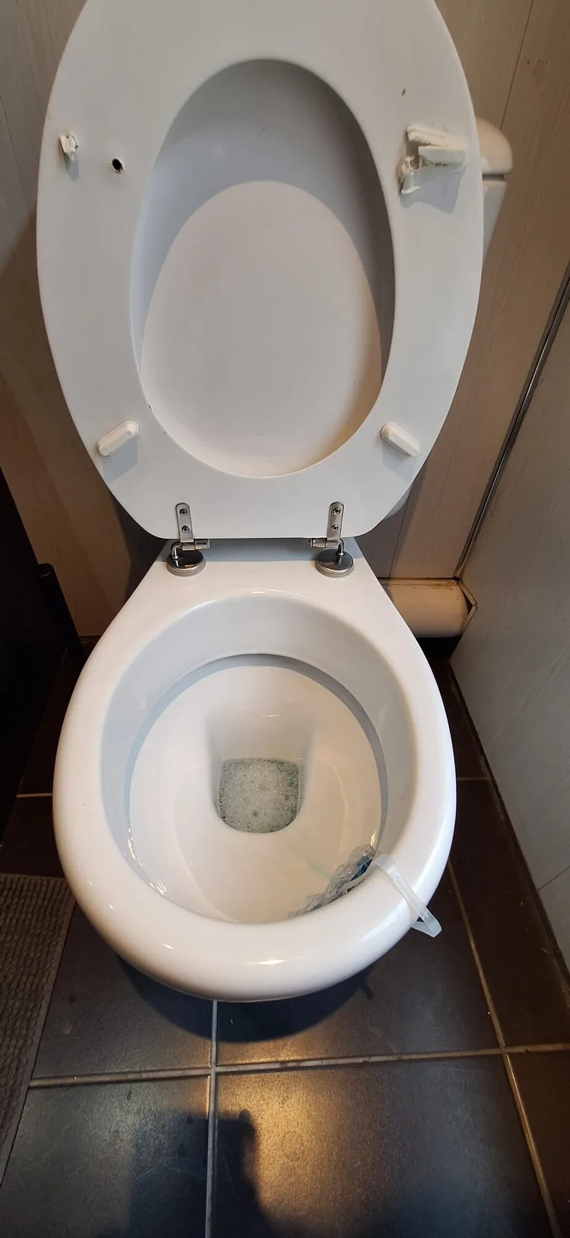 A toilet in a bathroom with the seat and lid raised.