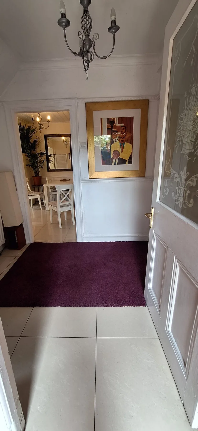 A hallway with a purple rug and a framed portrait on the wall.