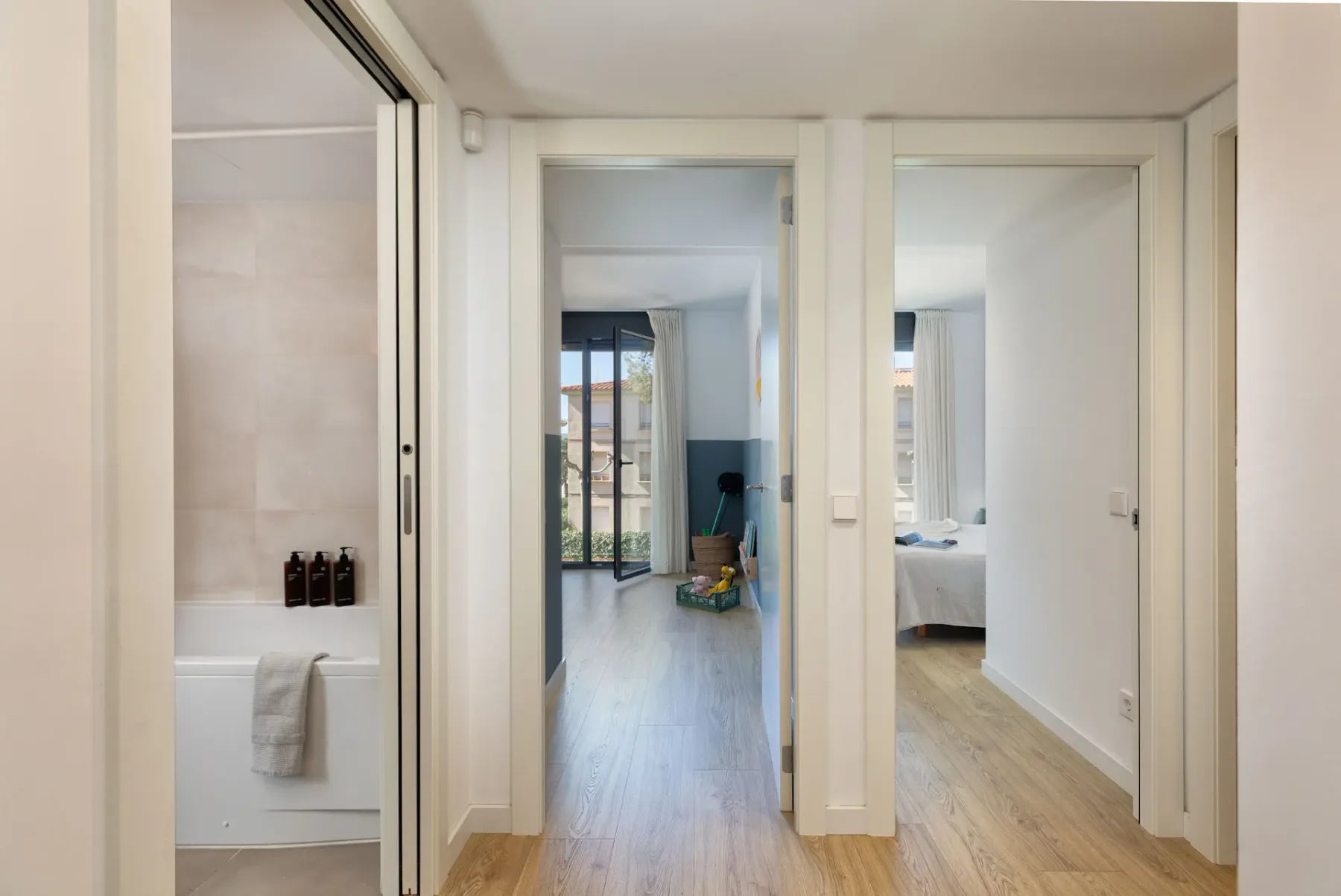 A bright hallway opens onto a bathroom and a bedroom.