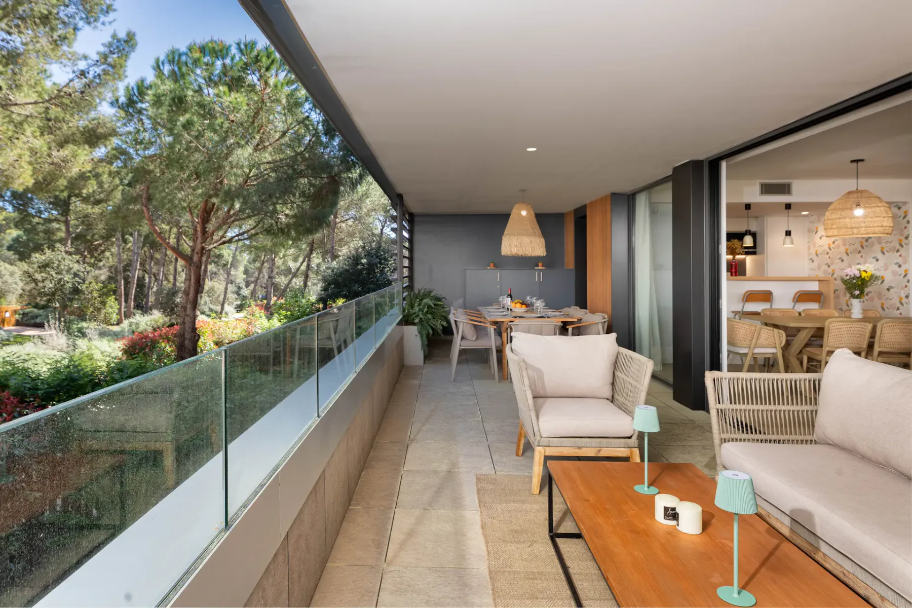 A furnished balcony overlooks trees and greenery, with an open dining area beyond.