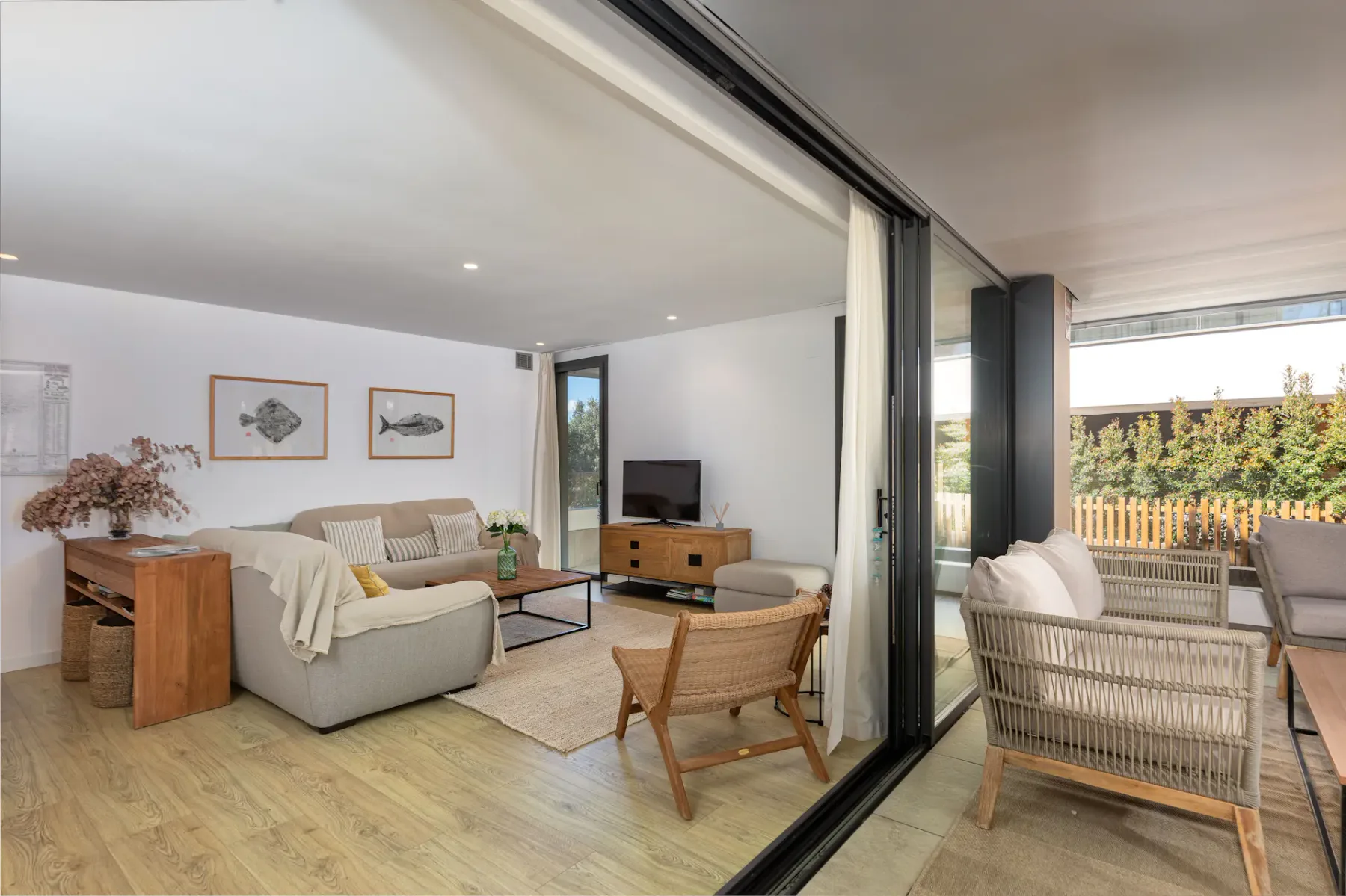 A living room opens onto a patio with wicker seating and a low table.