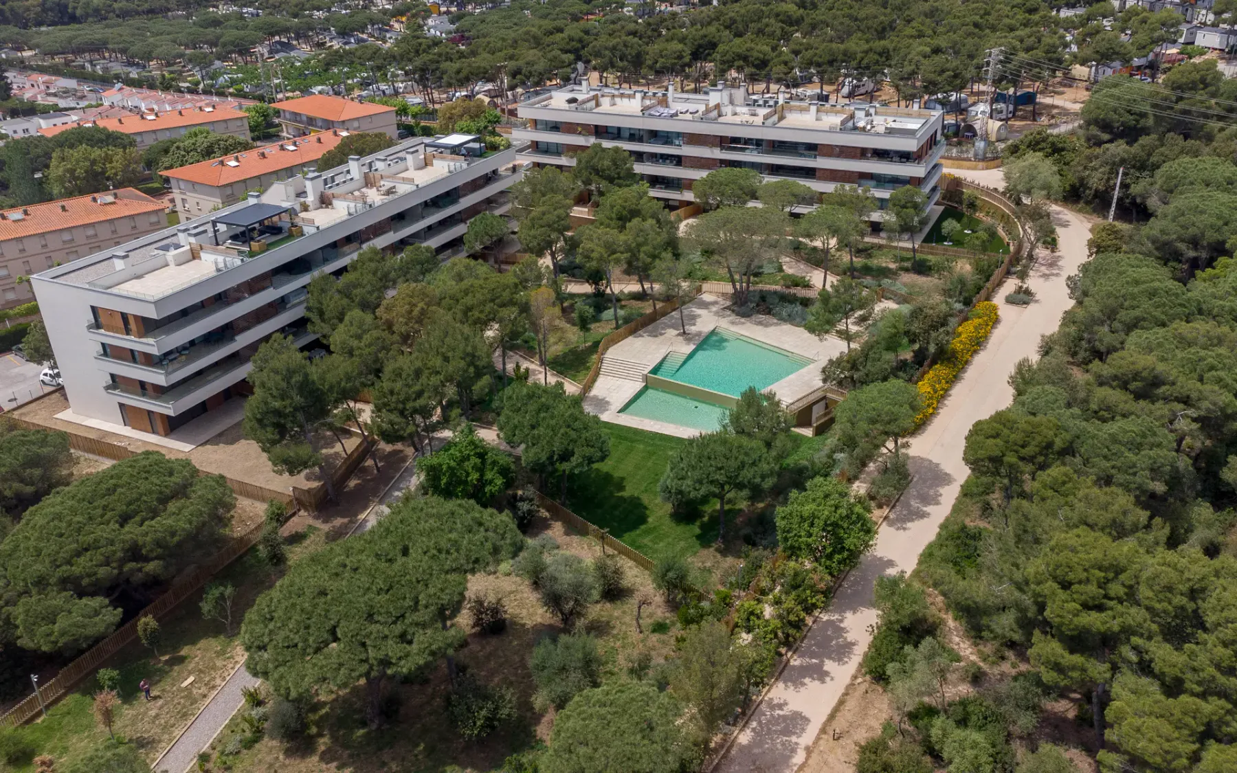 Shared amenity: Aerial view of apartment buildings with a swimming pool among trees.