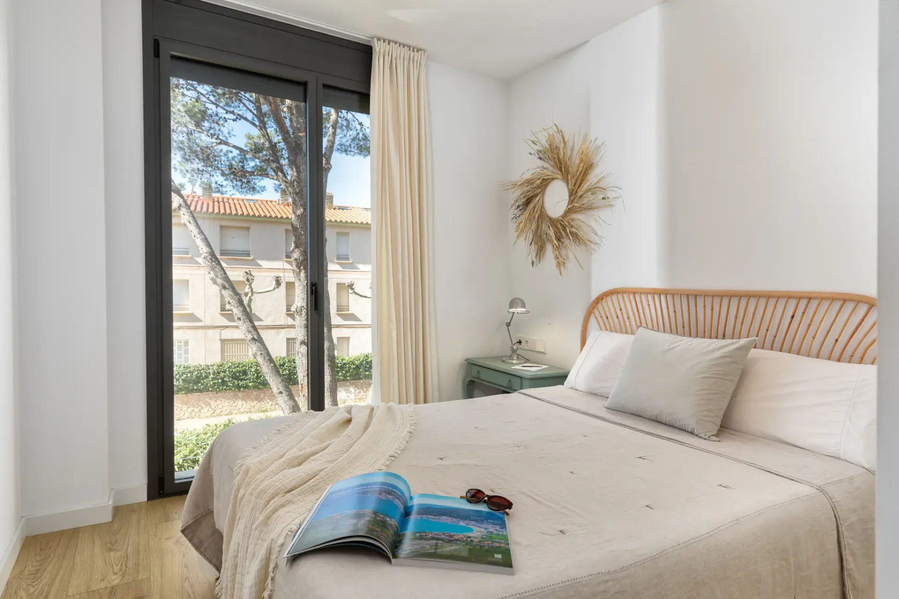 A bright bedroom with a large bed beside a window.