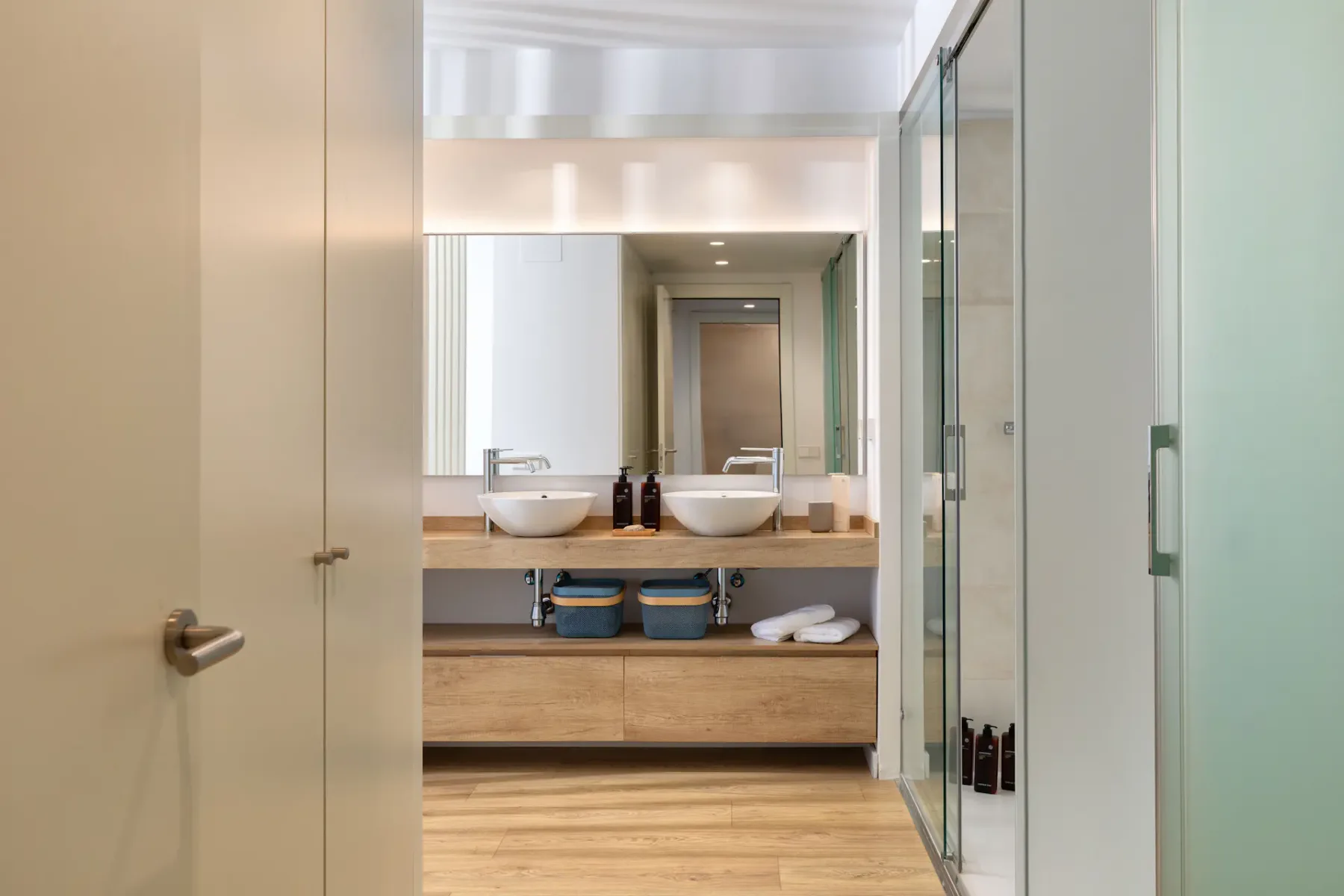 A bright bathroom with a double-sink vanity and glass shower.