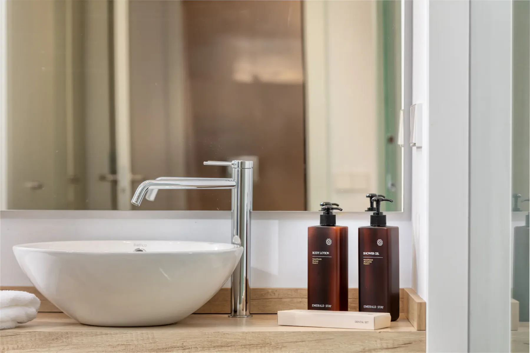 A bathroom vanity with a white vessel sink, faucet, and soap dispensers.