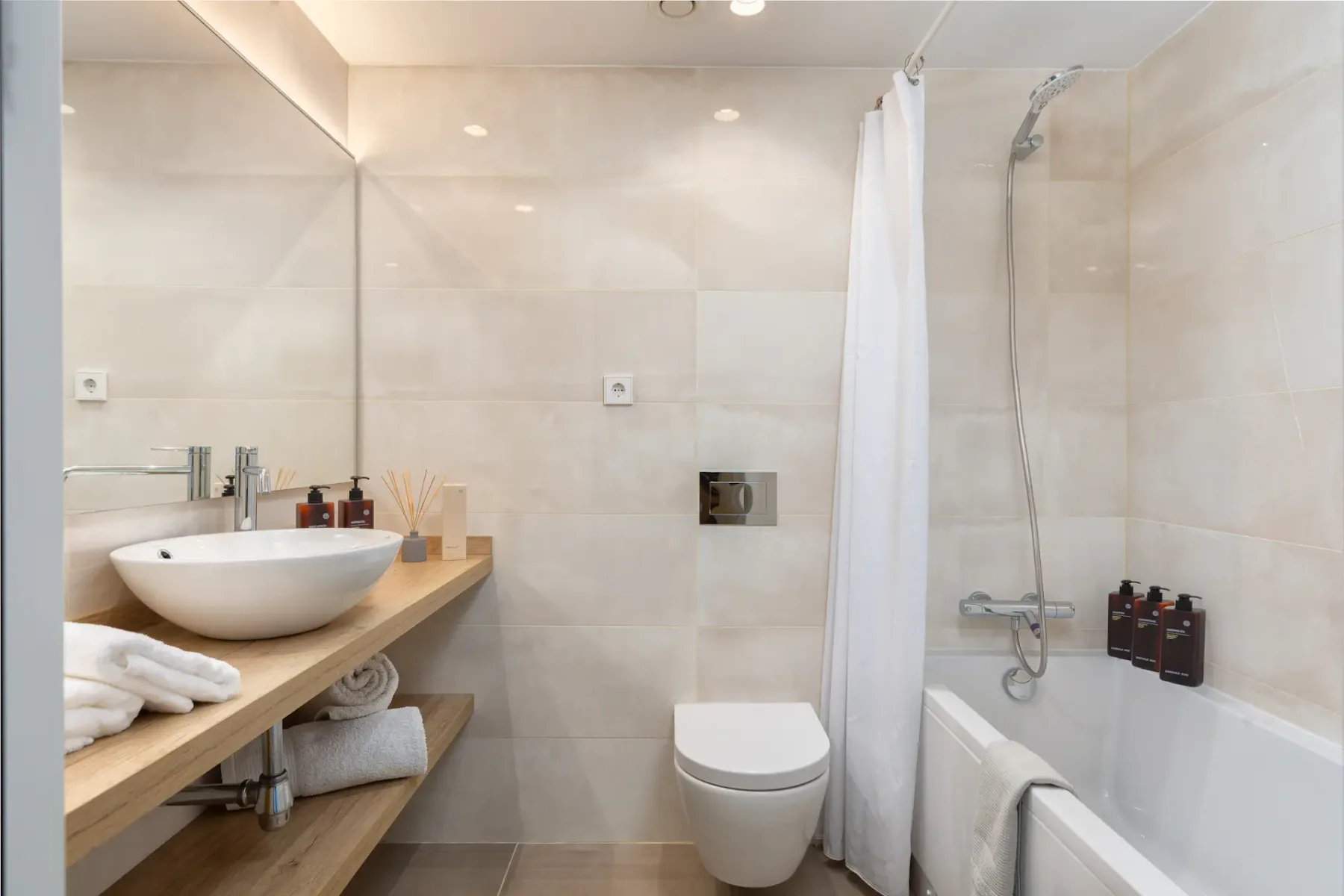 A tiled bathroom with a sink, toilet, and bathtub with a shower curtain.