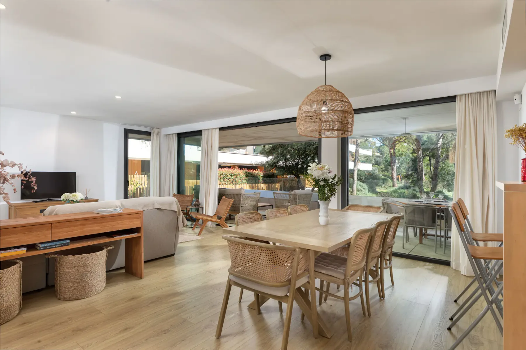Open-plan living and dining area with a wooden table beside large windows.