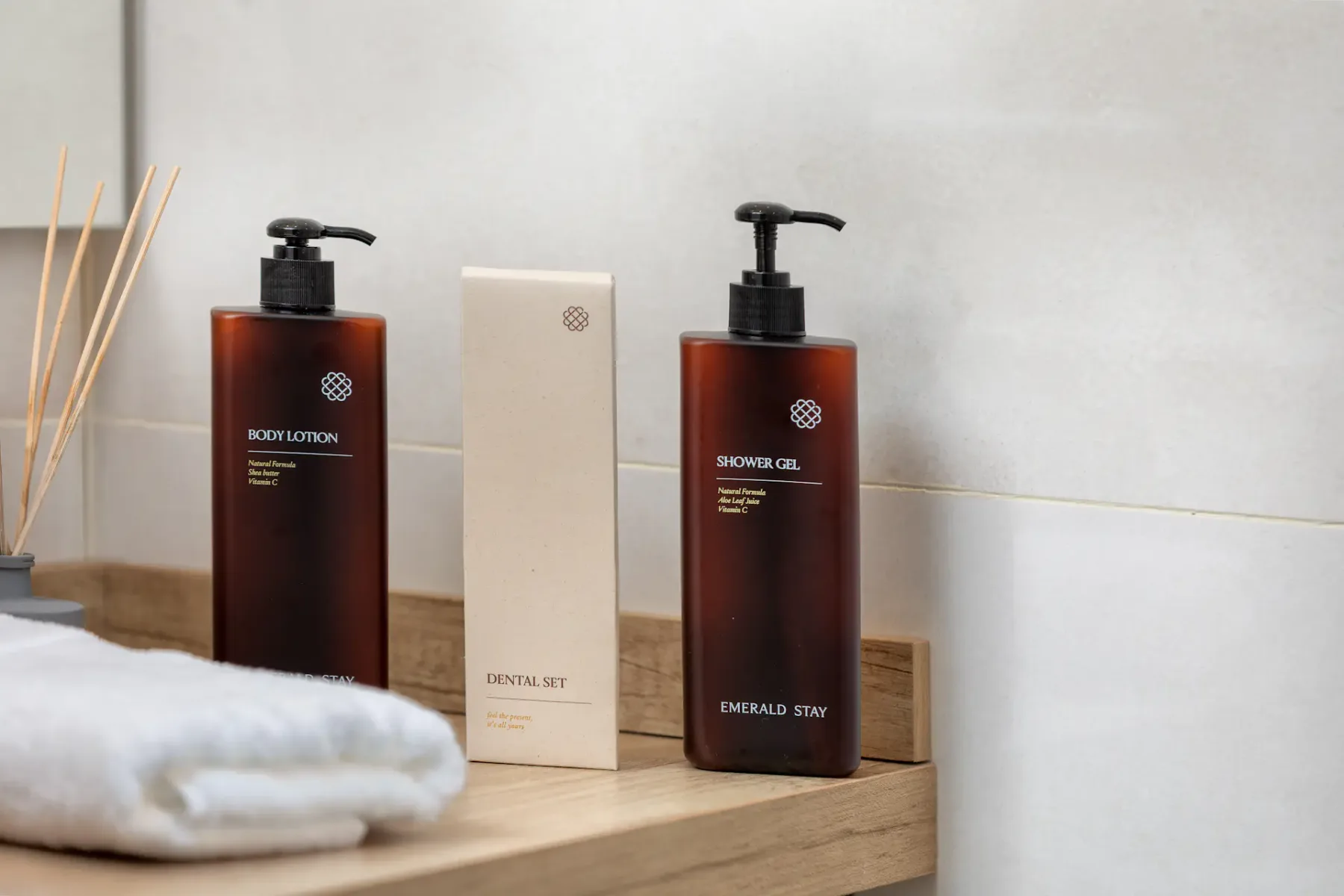Bathroom toiletries sit on a wooden counter beside folded towels and reed diffusers.