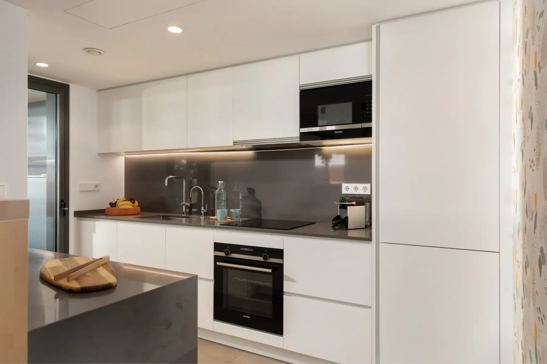 A modern kitchen with white cabinets, a dark countertop, and built-in appliances.