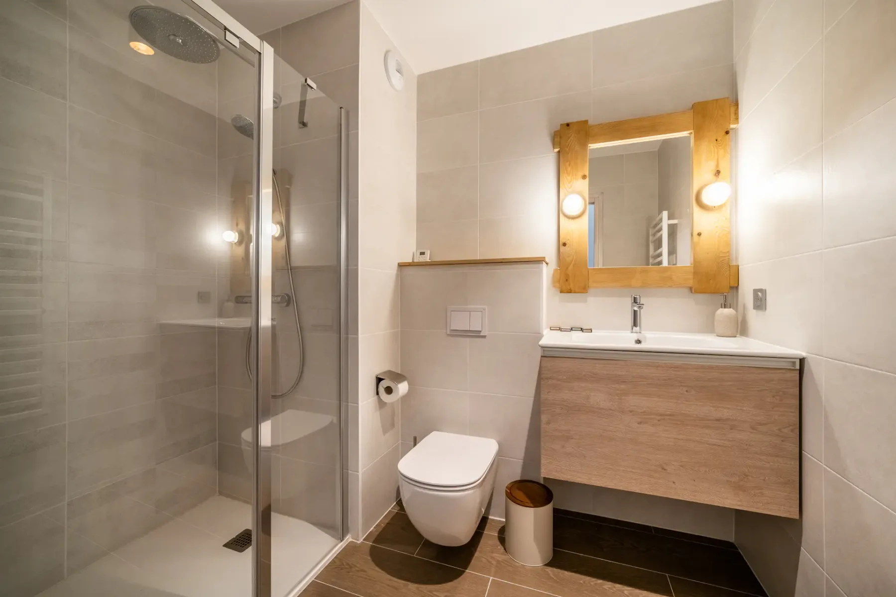 Un baño con azulejos, ducha de vidrio, inodoro y lavabo.