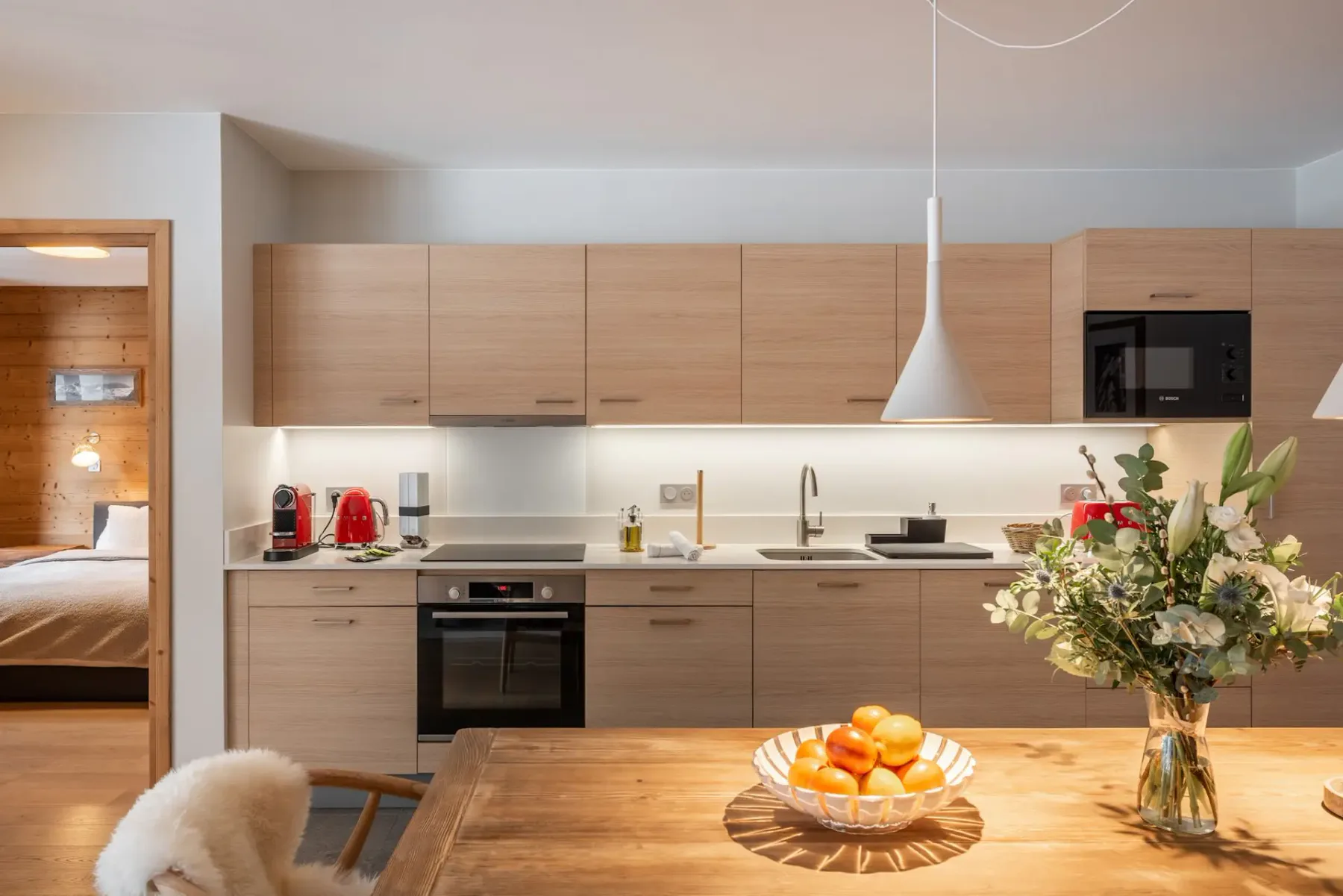 Una cocina moderna con gabinetes de madera se abre a una mesa de comedor.