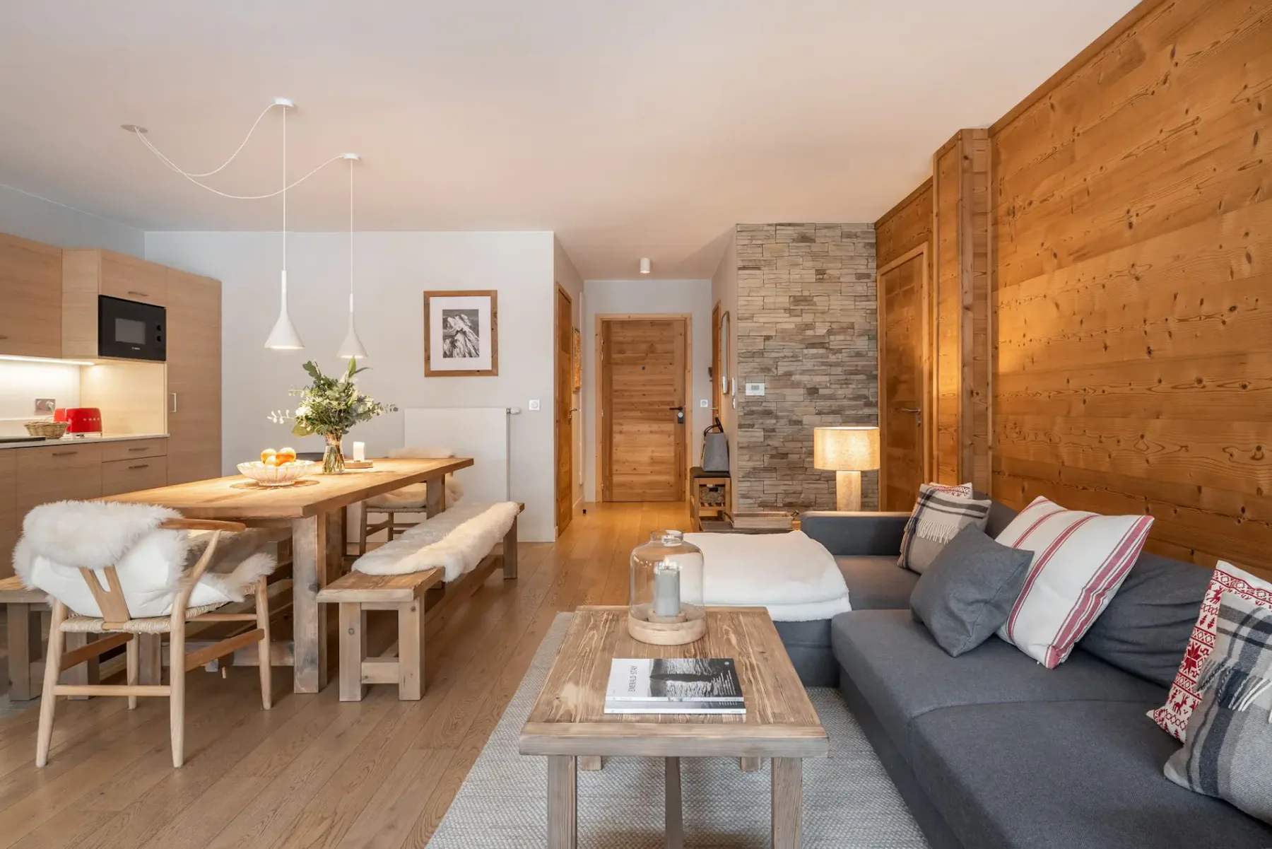 Una sala-comedor diáfana con una mesa de madera y asientos grises.