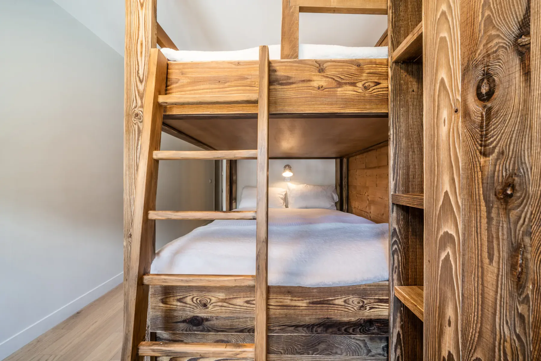 Una litera de madera con escalera está en un dormitorio.
