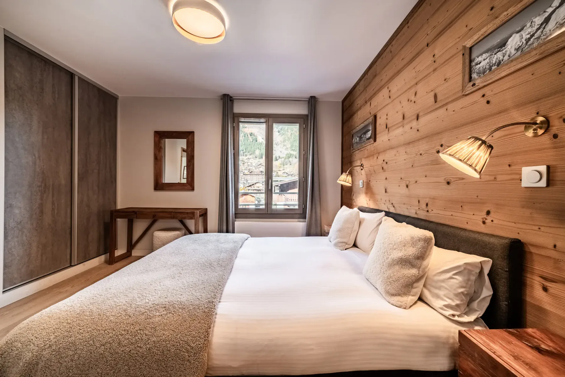 Un dormitorio con una cama grande, una pared revestida de madera y una ventana.
