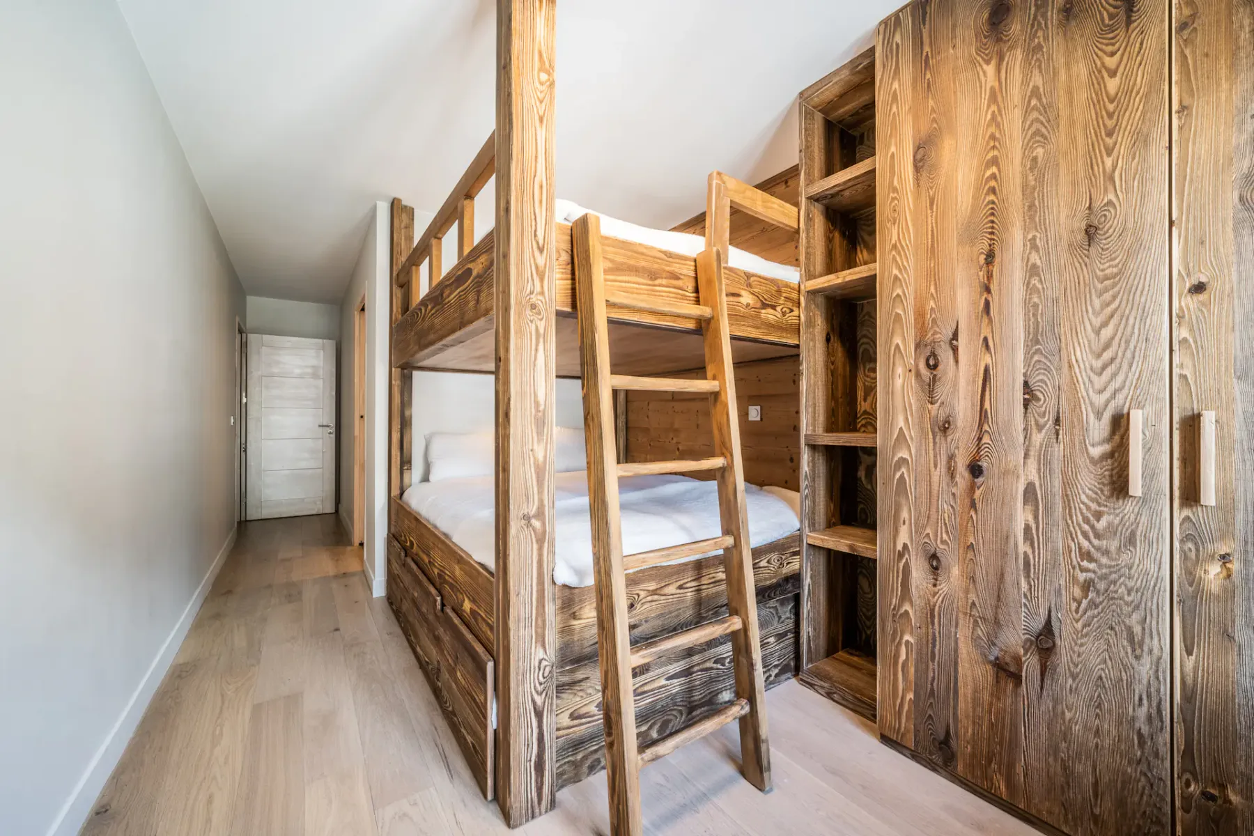 Una zona estrecha para dormir con literas de madera y espacio de almacenamiento integrado.