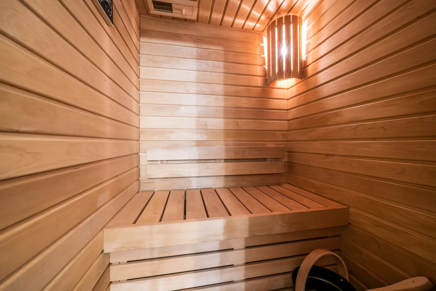 Una sauna revestida de madera, con un banco elevado y una luz encendida en la pared.