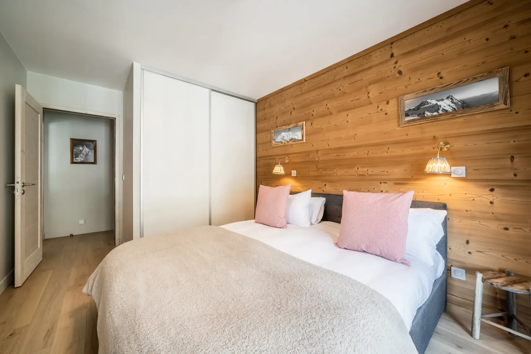 Un dormitorio con una cama doble junto a una pared revestida de madera.