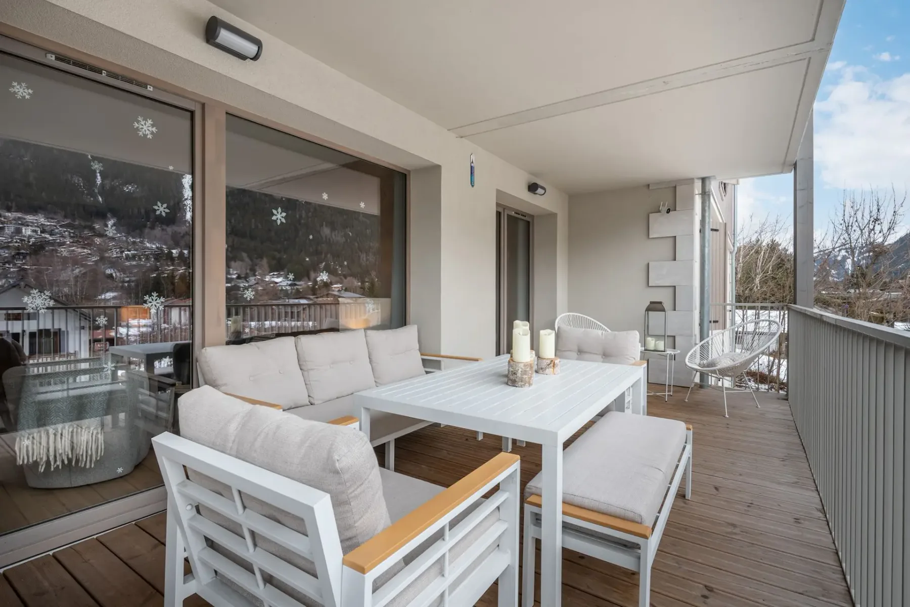 Una zona de estar al aire libre cubierta, con una mesa blanca y sillas acolchadas.