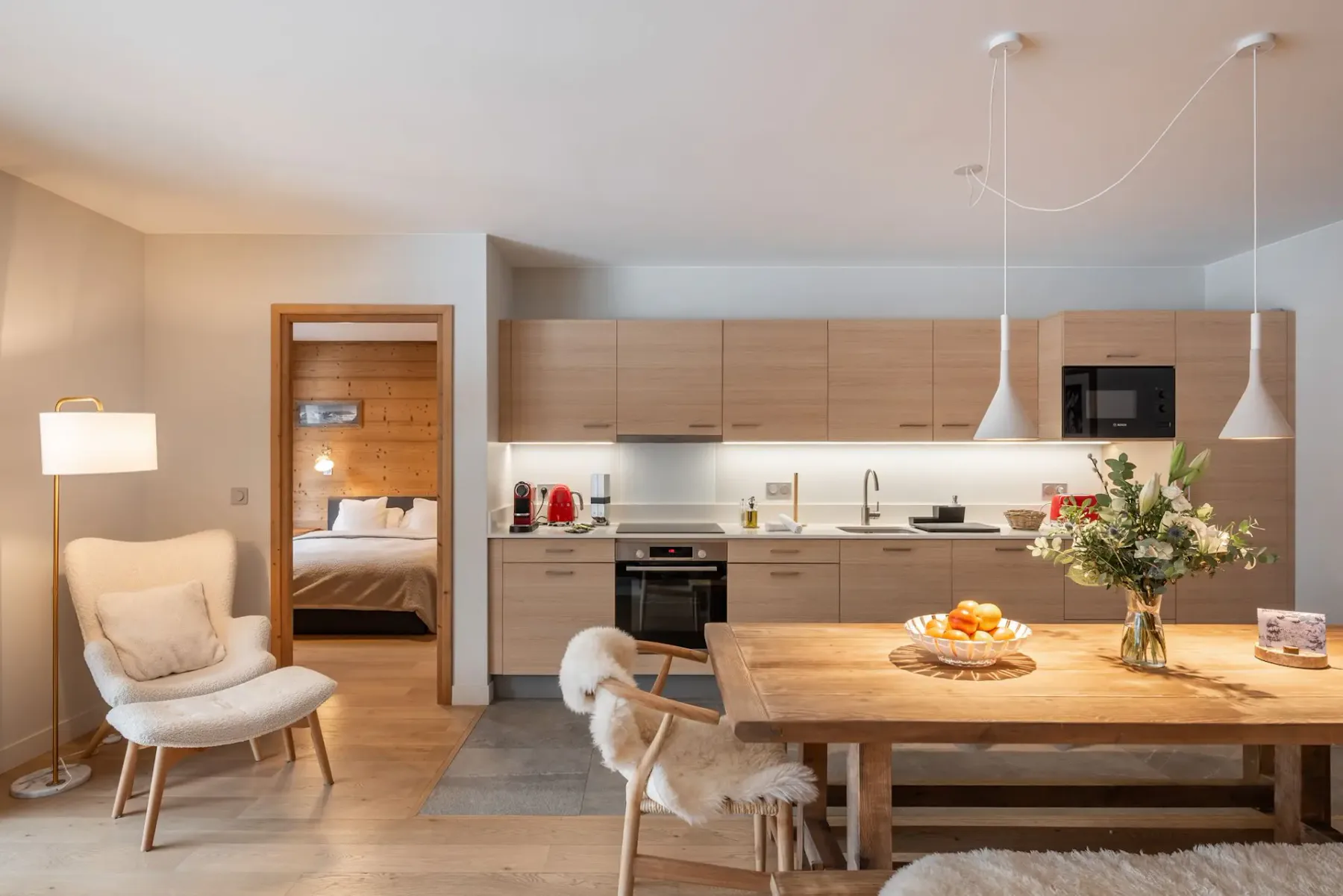 Una cocina y comedor de concepto abierto con una mesa de madera y asientos cercanos.