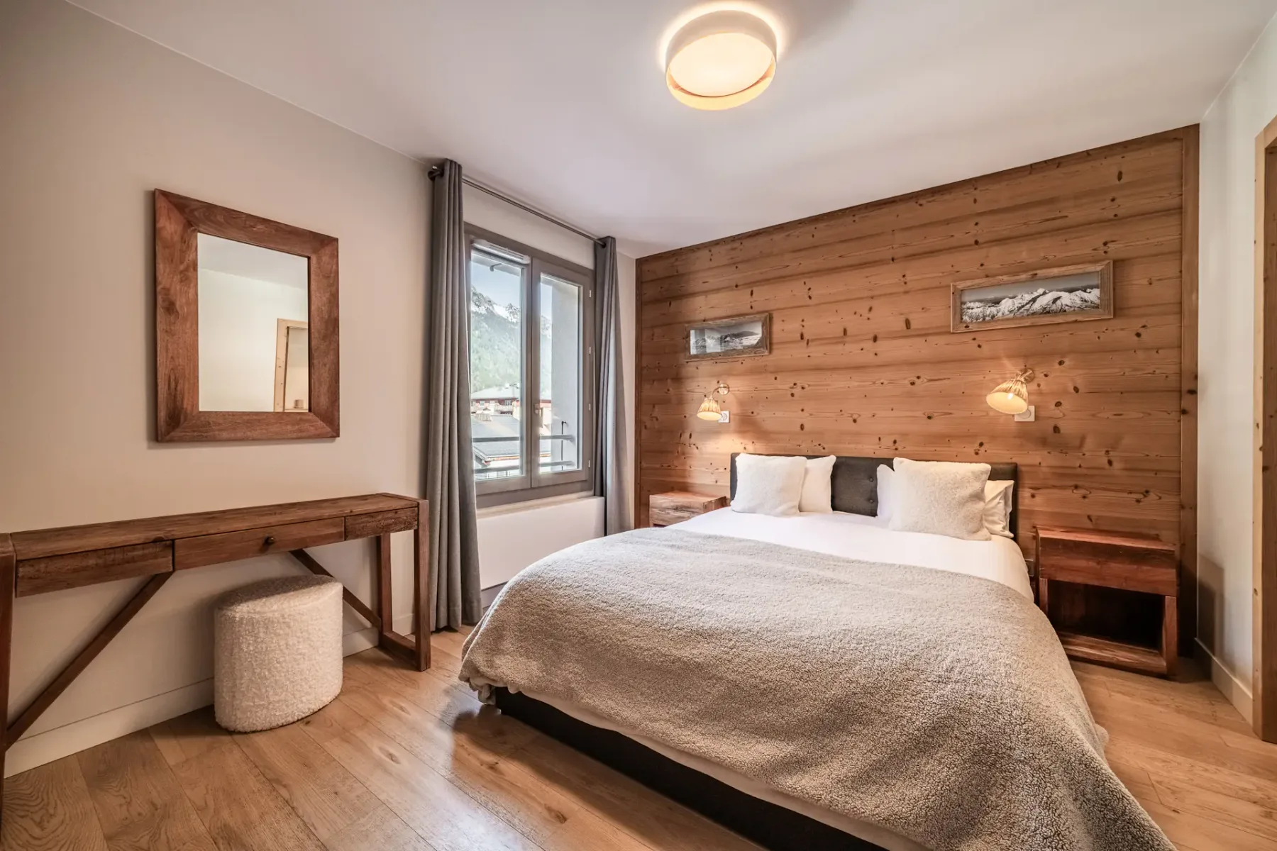 Un dormitorio con una cama junto a una pared revestida de madera y una ventana.