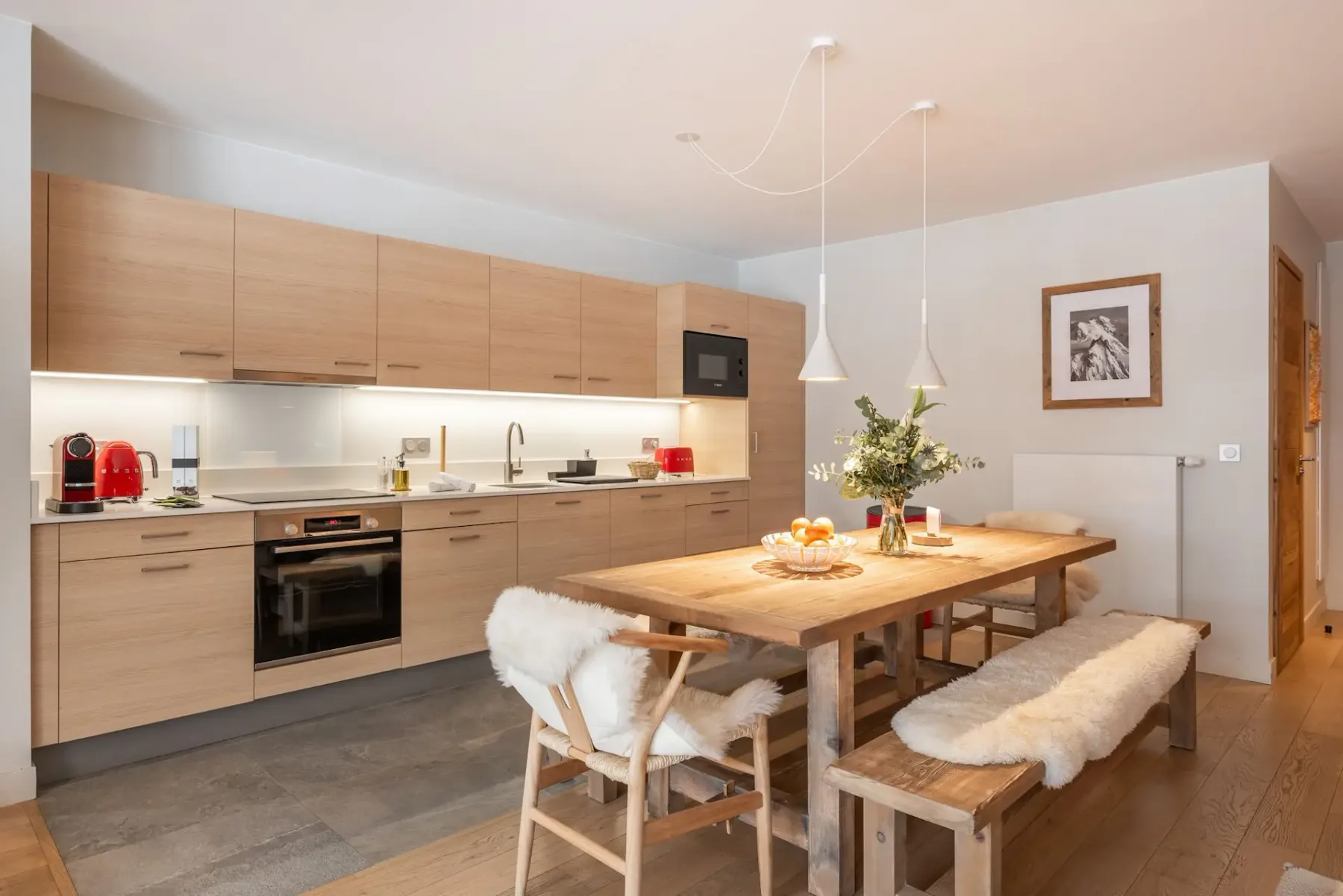 Una cocina luminosa con comedor, gabinetes de madera clara y una mesa amplia.