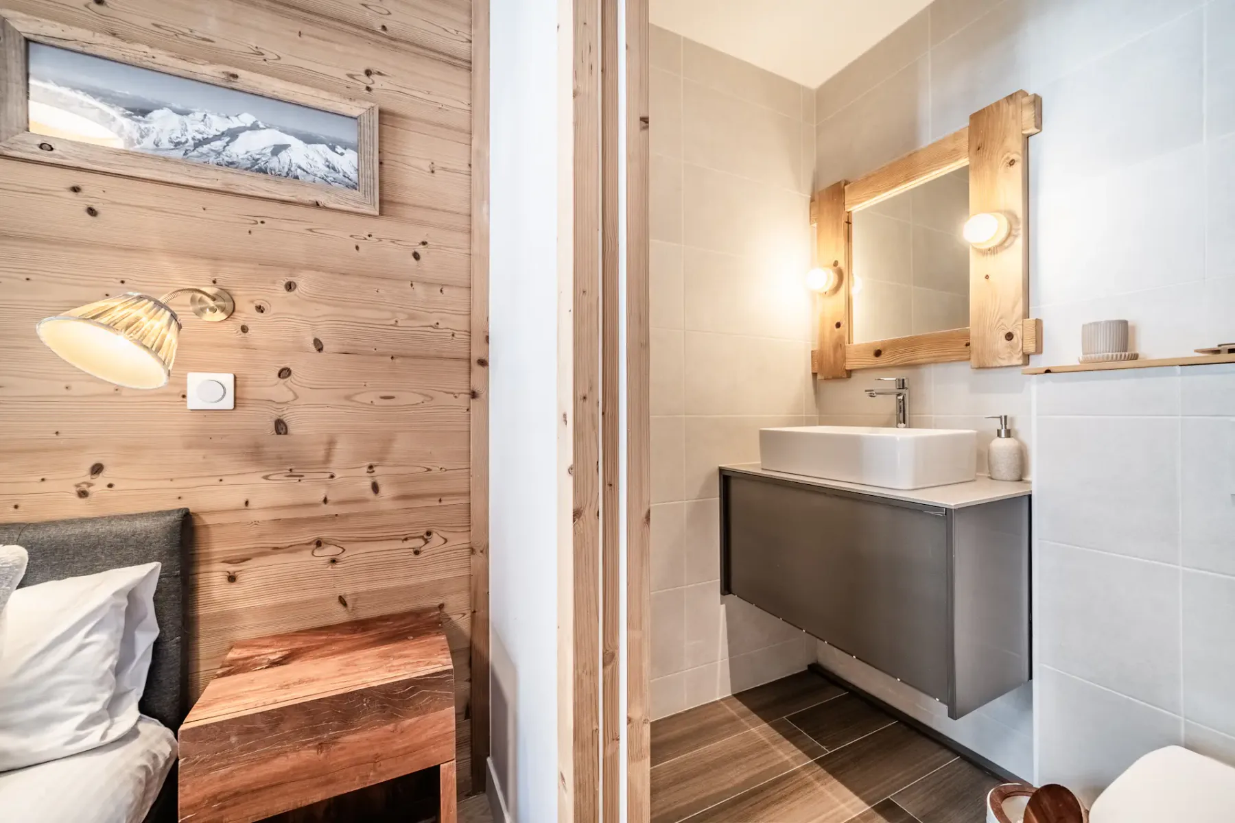 Un dormitorio junto a un baño, con una pared revestida de madera y un lavabo.
