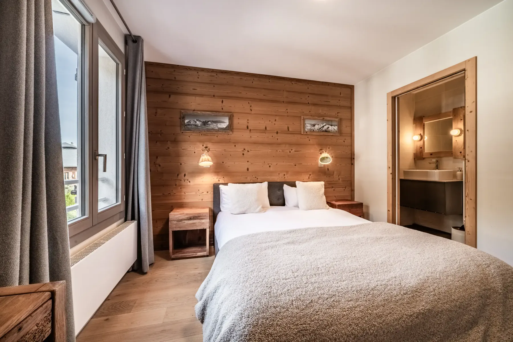 Un dormitorio con una cama, una pared revestida de madera y una ventana grande.