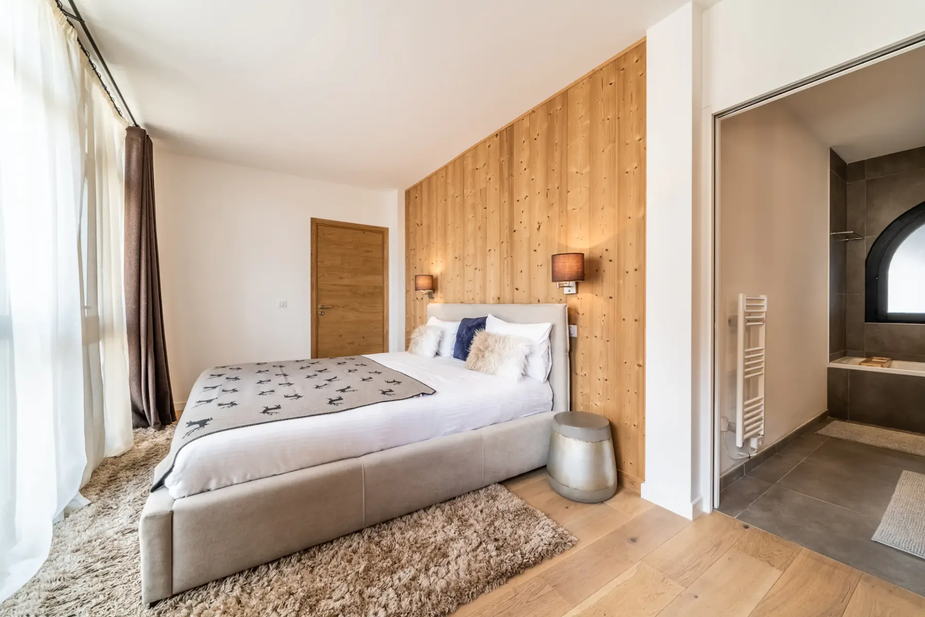 Dormitorio con una cama junto a una pared revestida de madera y una puerta abierta al baño.
