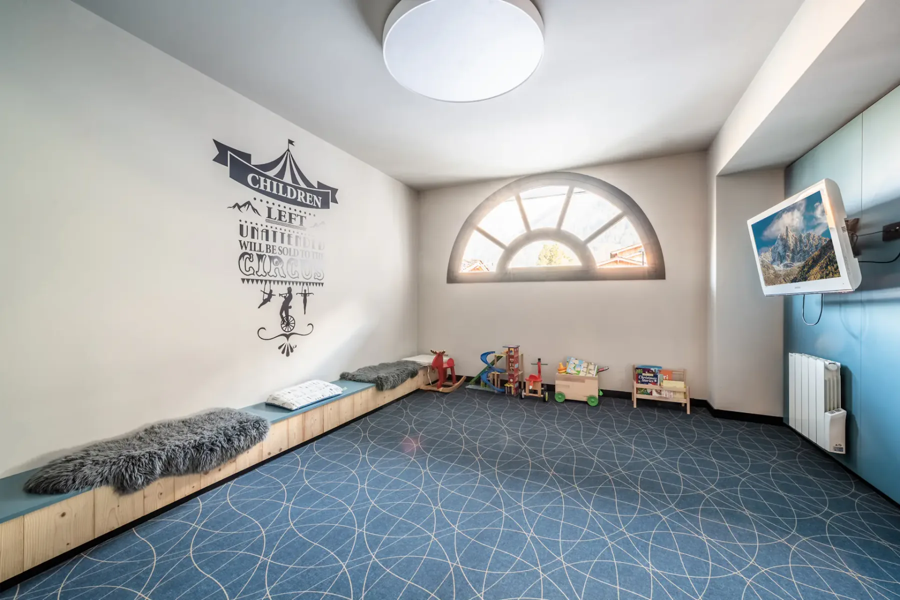 Una sala de juegos infantil con juguetes y un banco acolchado junto a la pared.