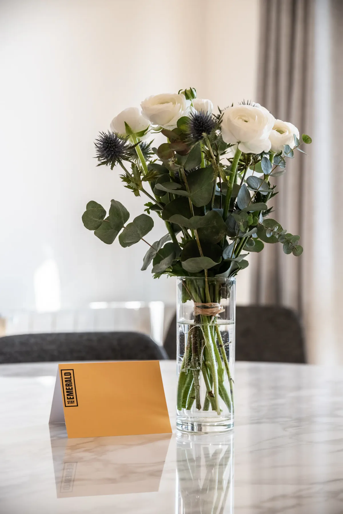 Un ramo de flores blancas está en un jarrón de vidrio sobre una mesa.