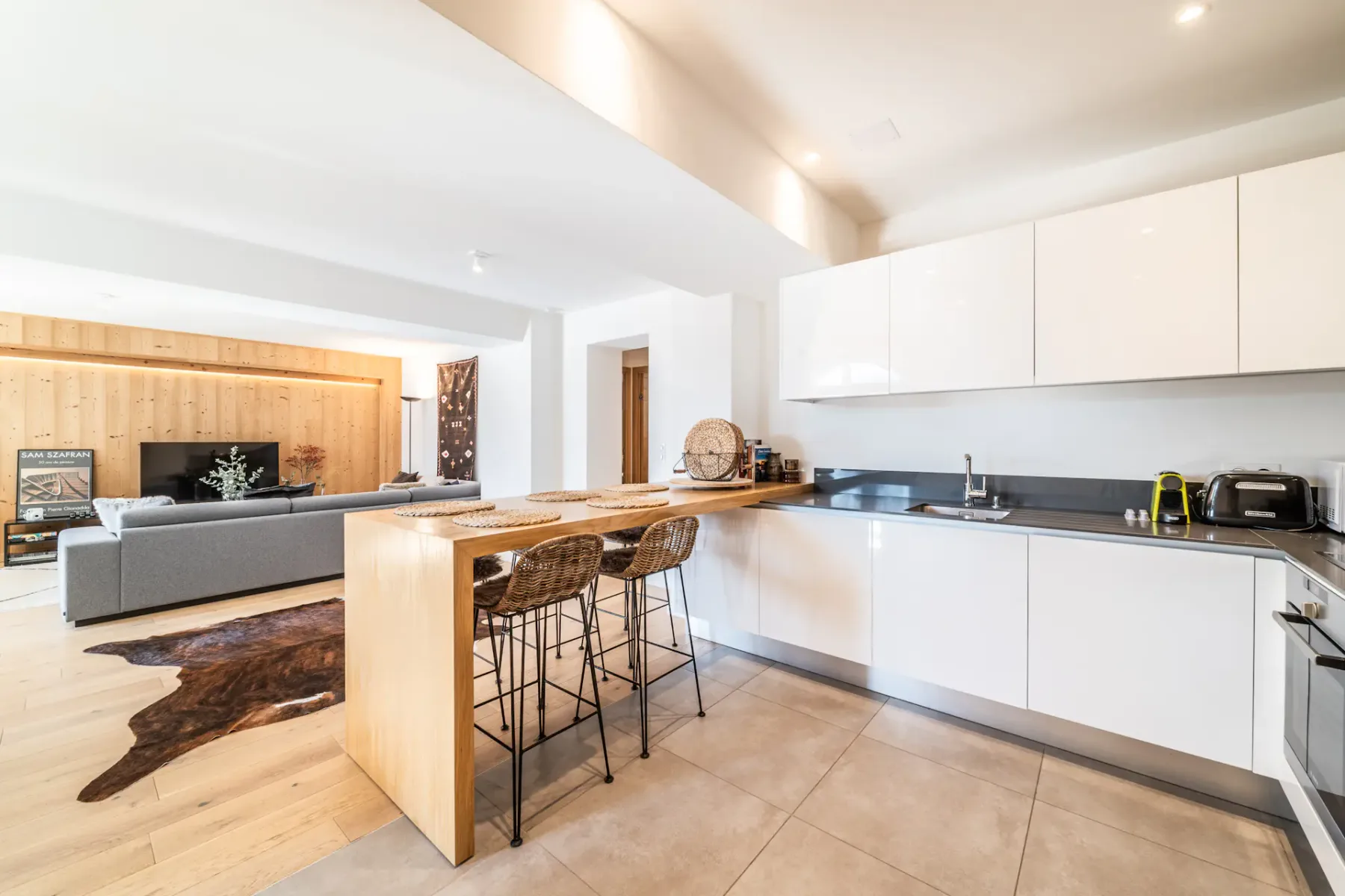 Cocina y sala de estar de concepto abierto, con barra de madera y asientos.