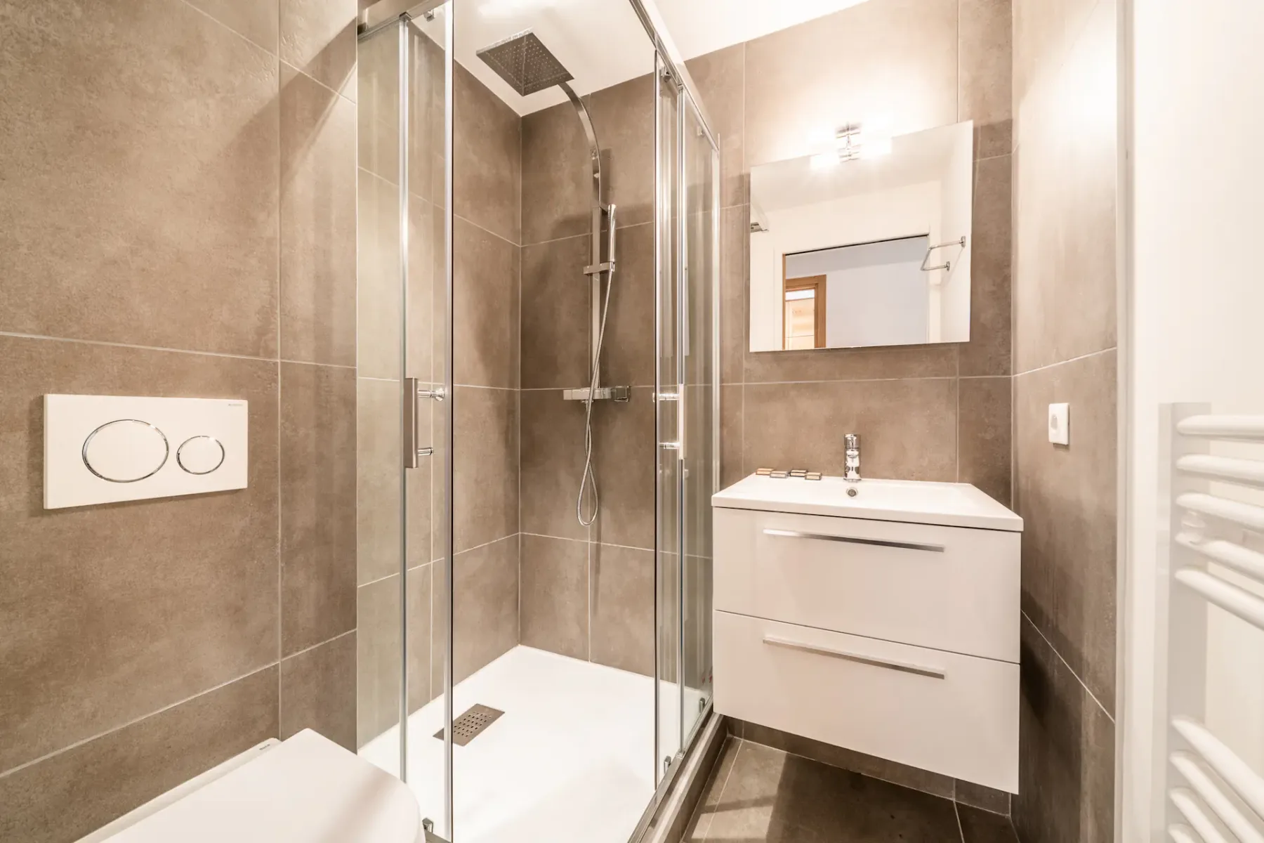 Un baño con azulejos, una ducha de vidrio y un lavabo con mueble.