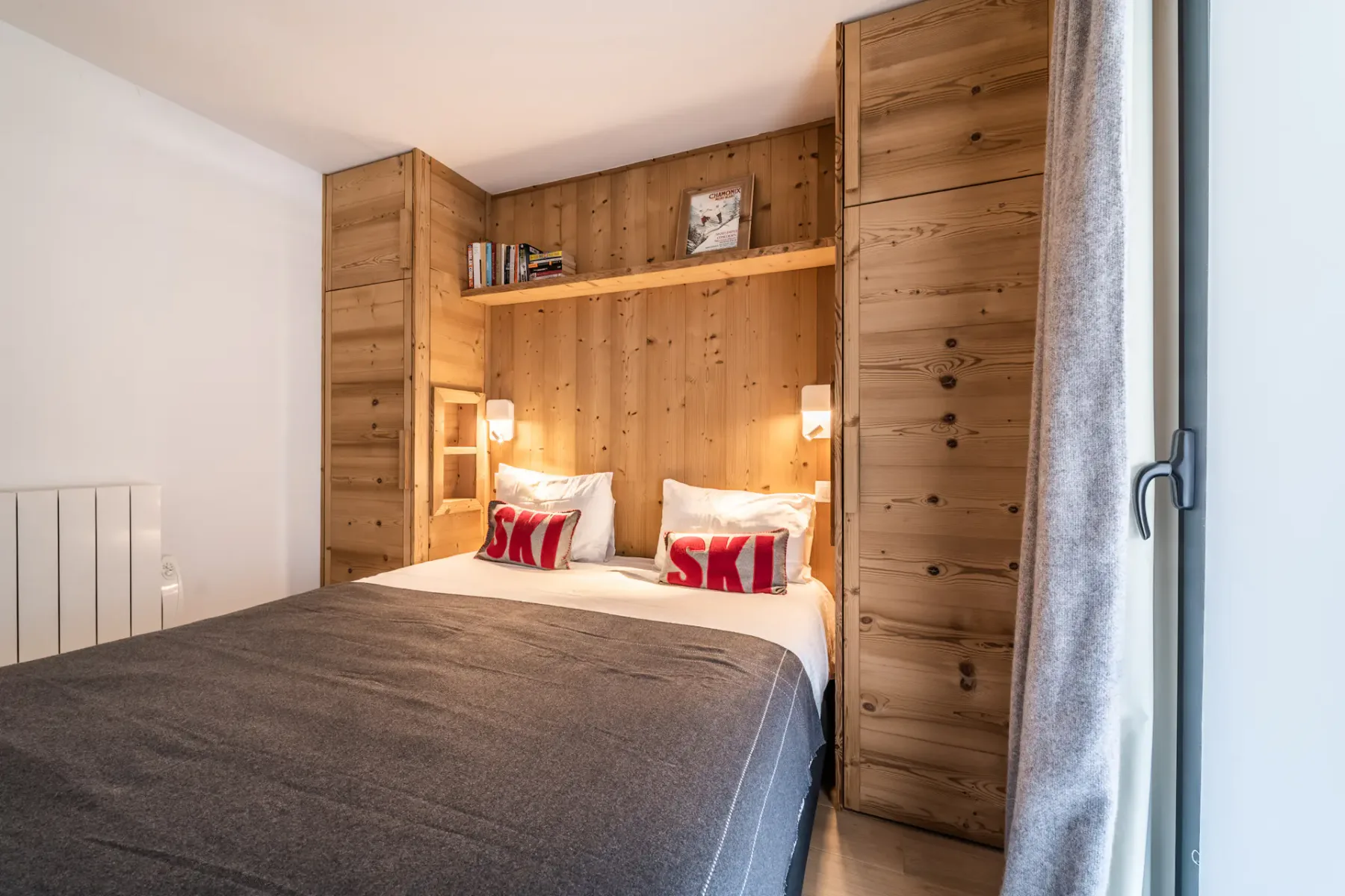 Un dormitorio con una cama frente a una pared revestida de madera.