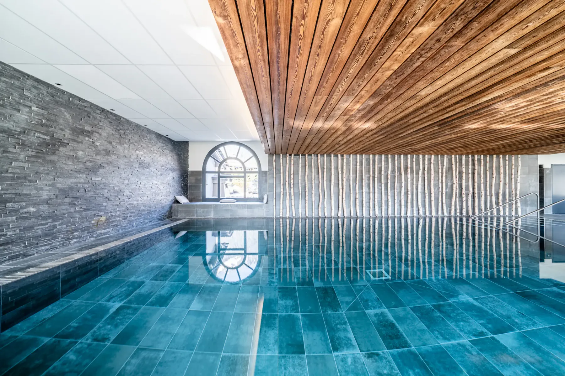 Una piscina cubierta con agua azul bajo un techo revestido de madera.