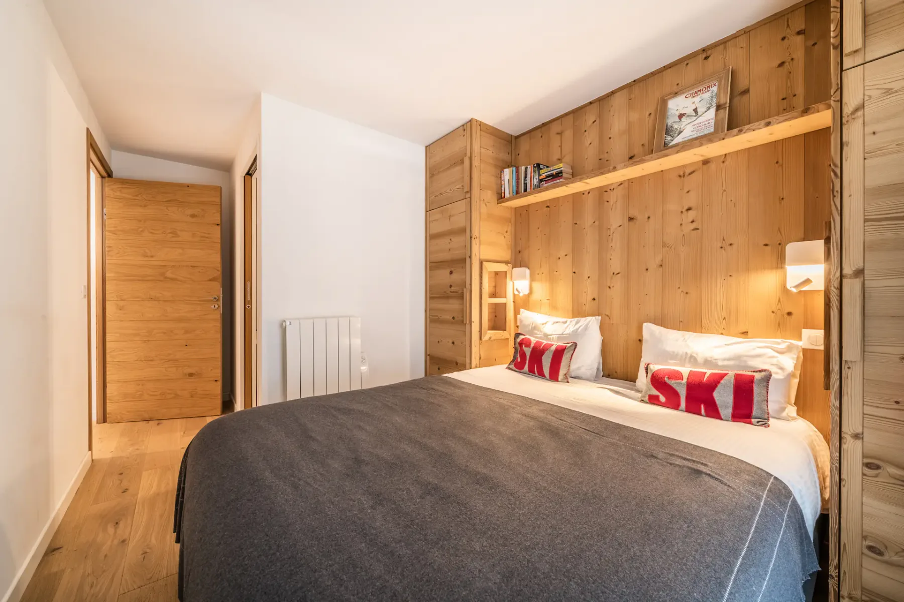 Un dormitorio con una cama junto a una pared revestida de madera y una puerta de madera.