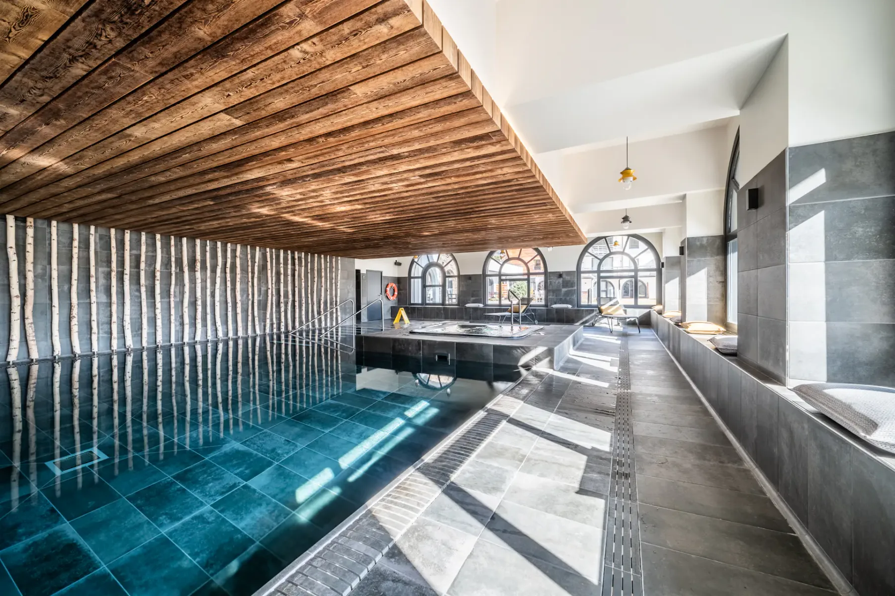 Una piscina cubierta con ventanas arqueadas y un techo de madera.