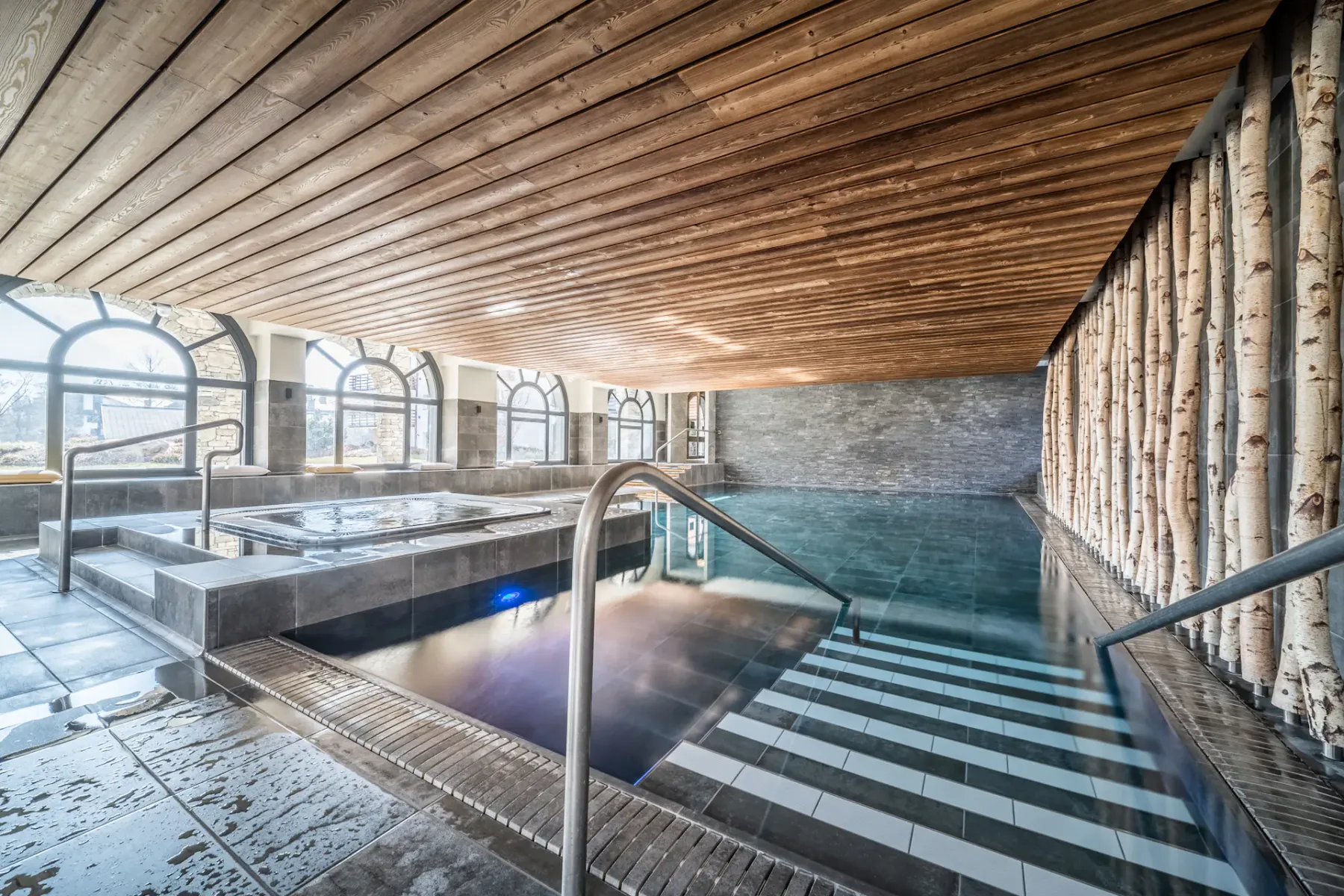 Piscina cubierta con escalones y techo revestido de madera.