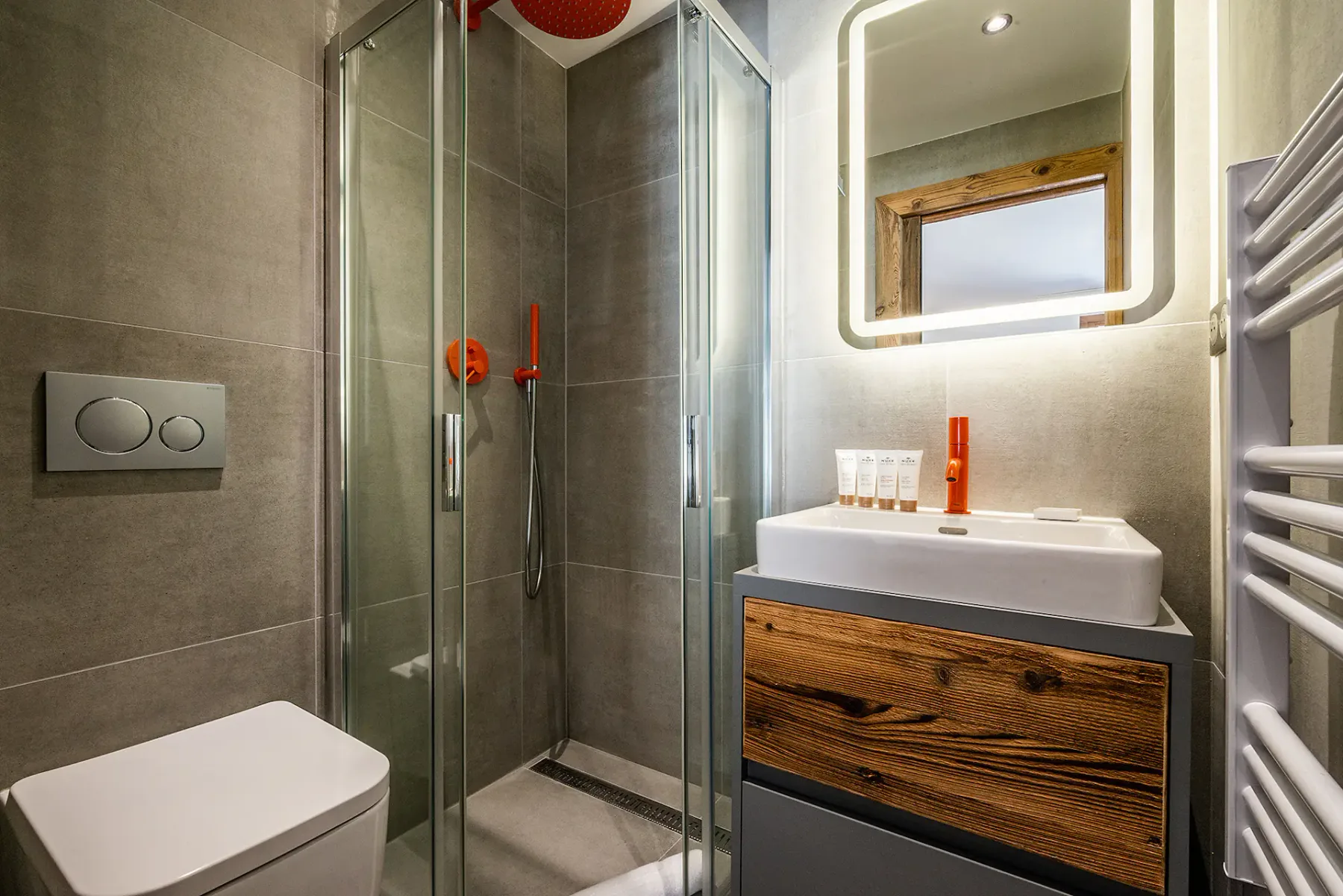 Un baño moderno con ducha de vidrio, lavabo y espejo iluminado.