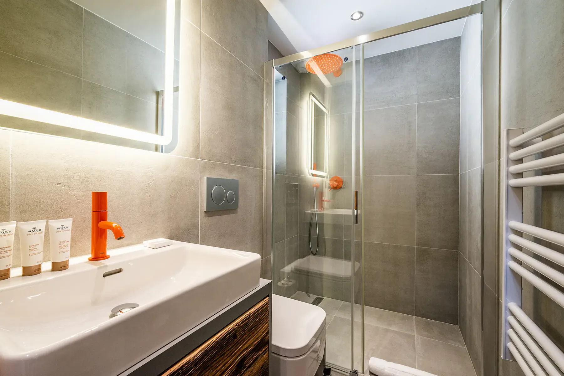 Un baño alicatado con ducha de vidrio, lavabo y toallero de pared.